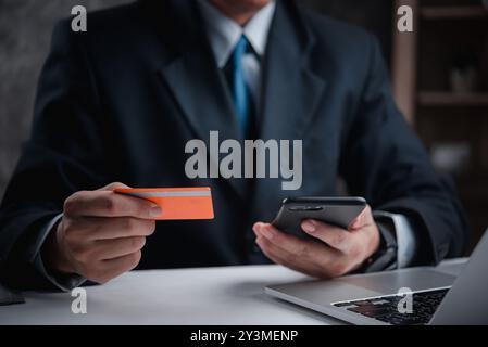 Businessman in suit holding credit card, making online payment with smartphone. Represents digital finance, secure transactions, e-commerce. Ideal for Stock Photo