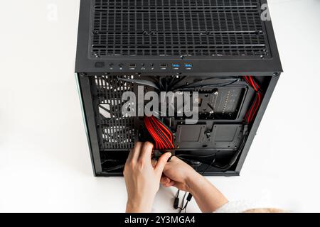 Person Expertly Installing Multiple Hardware Components into a Sleek Black Computer Tower Case Stock Photo