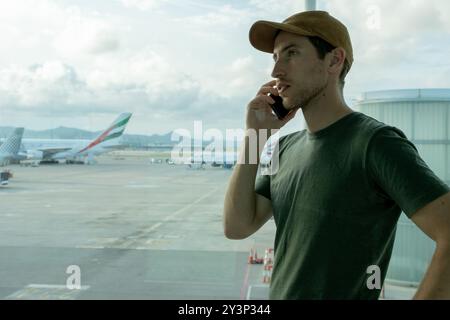 Traveler man at the airport with his smartphone waiting to get on his plane. Tourism, travel an destination concept Stock Photo