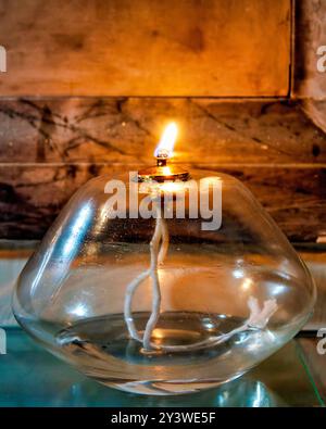 A traditional glass oil lamp burning in a church, is used for lighting and symbolizing prayer and devotion. Stock Photo