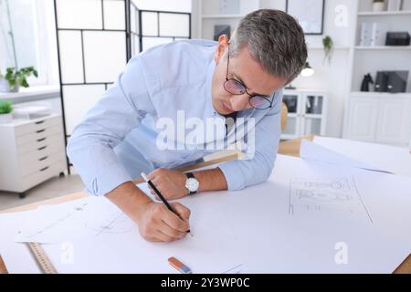 Architect making engineering drawing at table in office Stock Photo