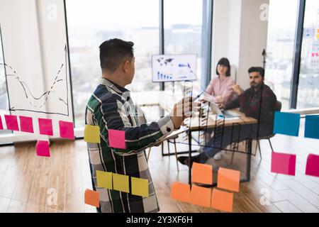 Business meeting with team brainstorming on charts and sticky notes Stock Photo