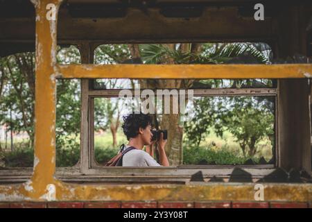 Man pointing camera to taking photo. Side view of young man with her camera taking picture. Young Male shots picture from behind the window. Stock Photo