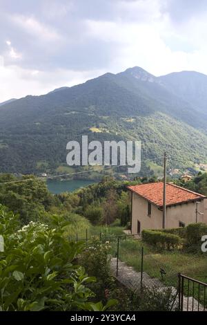 Village lying on a cliff in the mountains with a lake in the valley below on a sunny day Stock Photo