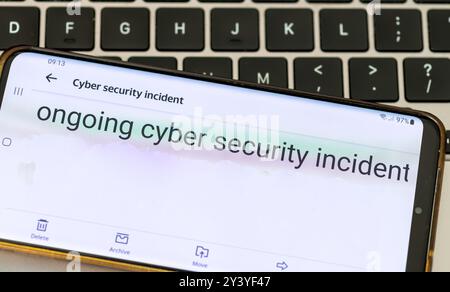 Close up of a message on a mobile phone from a company informing its clients of an ongoing cyber security incident. Stock Photo