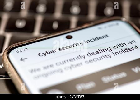 Close up of a message on a mobile phone from a company informing its clients of an ongoing cyber security incident. Stock Photo