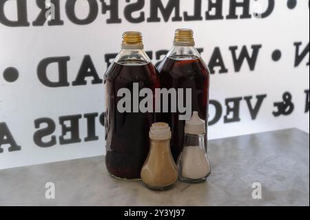 Vinegar, salt and pepper condiment bottles on a cafe table, photographed against a window with reversed lettering visible through the glass. Stock Photo