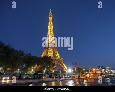 Eiffel Tower at night, illuminated, with its reflection in the water and people in the foreground, paris, france Stock Photo