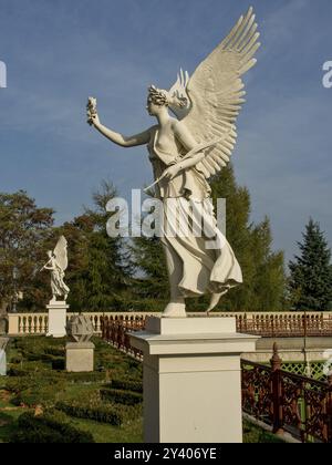 Angel statue in a garden with historical architecture, depicted with outstretched wings, Schwerin, Mecklenburg, Germany, Europe Stock Photo