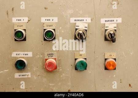 Close-up of a vintage industrial control panel with various buttons and switches labeled for operating fans and burners Stock Photo