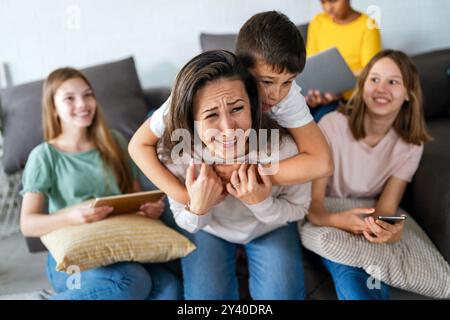 Happy woman with multiethnic children using digital gadgets. Family and modern technology addiction. Stock Photo