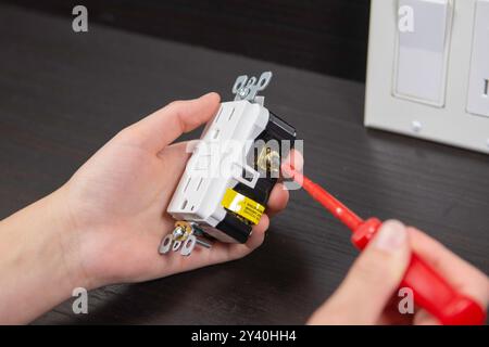 Checking the electrical outlet before installing it in a junction box on the wall Stock Photo