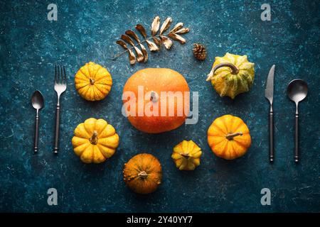 Autumn Pumpkin on blue vintage backdrop with kitchen utensils fork, knife, spoon. Thanksgiving Background Stock Photo