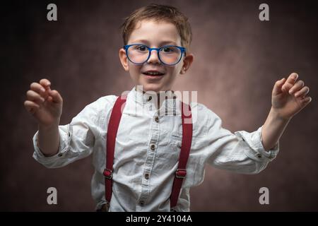 Smart kid portrait with glasses dressed in vintage clothes smiling against camera, schoolboy, student in school Stock Photo