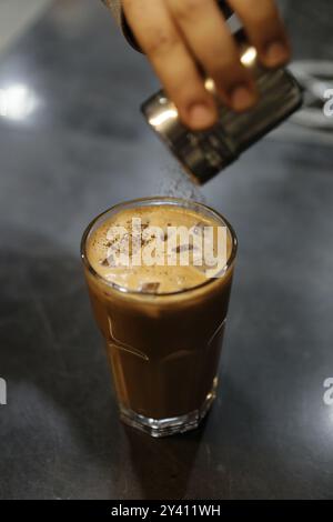 A refreshing iced coffee topped with cocoa powder, perfect for a hot day Stock Photo