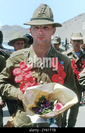 A first Soviet Army soldiers stand holding flowers after crossing the Oxus River at the Soviet-Afghan border, May18, 1988 in Termez, Uzbekistan, Soviet Union.  The Soviet Union invaded Afghanistan in December 1979 and marked the end of the occupation with a ceremony after the first armored column crossed the Friendship bridge beginning the withdrawal of forces. Stock Photo