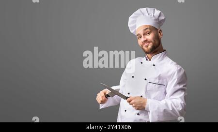 Funny Chef Man Sharpening Knives Standing, Studio Shot, Panorama Stock Photo