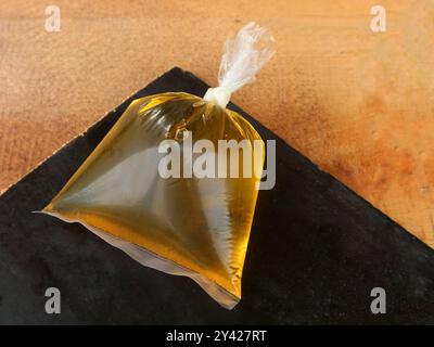 Cooking oil in a plastic bag is displayed on a wooden surface background Stock Photo