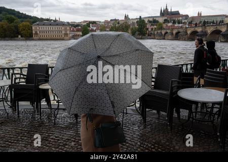 Prague, Czech Republic. 15th Sep, 2024. Woman with umbrella observes the rising water level of Vltava river on a rainy day in Prague near iconic Charles Bridge and Prague Castle. Heavy rains during the recent days have caused water levels to rise in Vltava river, which caused flood emergency warning. Floods caused by heavy rains have been battering region of central and eastern Europe, including Czech Republic, Poland, Austria, Slovakia and Romania since 13 September 2024. (Credit Image: © Tomas Tkacik/SOPA Images via ZUMA Press Wire) EDITORIAL USAGE ONLY! Not for Commercial USAGE! Stock Photo