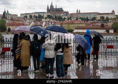 Prague, Czech Republic. 15th Sep, 2024. Group of tourists with umbrellas observe rising water levels of Vltava river on a rainy day in Prague near iconic Charles Bridge and Prague Castle. Heavy rains during the recent days have caused water levels to rise in Vltava river, which caused flood emergency warning. Floods caused by heavy rains have been battering region of central and eastern Europe, including Czech Republic, Poland, Austria, Slovakia and Romania since 13 September 2024. (Photo by Tomas Tkacik/SOPA Images/Sipa USA) Credit: Sipa USA/Alamy Live News Stock Photo