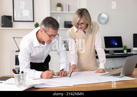 Architects making engineering drawing at wooden table in office Stock Photo