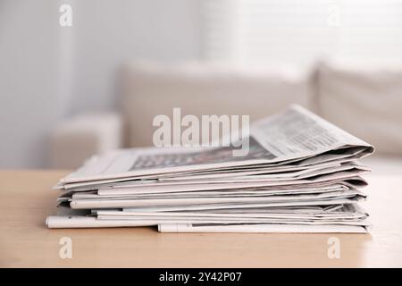 Stack of newspapers in different languages on table indoors Stock Photo