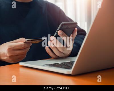 Secure payment concept. Black smart mobile smart phone in businessman hand while holding credit card for checking payment, online shopping, exchange o Stock Photo