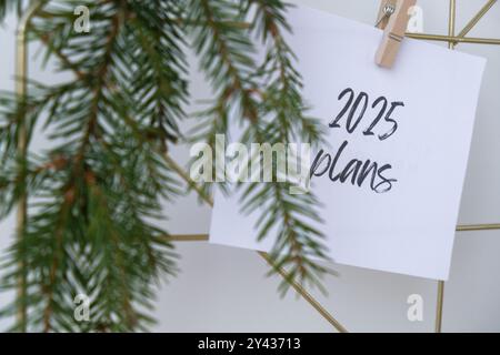 2025 PLANS text on white paper note on vision board with Christmas decor. New year aims resolutions. New me you concept visualizing dreams  Stock Photo