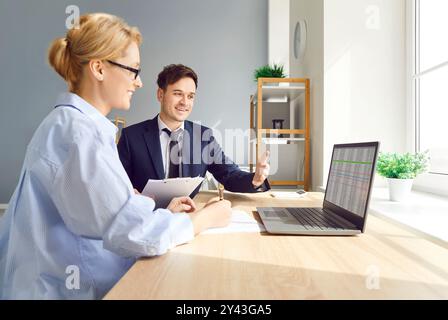 Colleagues Working With Graphs And Laptop In Office Meeting Stock Photo