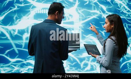 Programmers using devices and AI neural networks modeled after human brain to solve complex problems. Workers using artificial intelligence deep learning to look at data and complete tasks, camera A Stock Photo