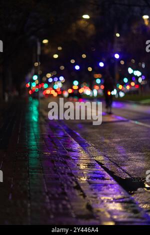 Wet city street with colorful bokeh lights at night Stock Photo