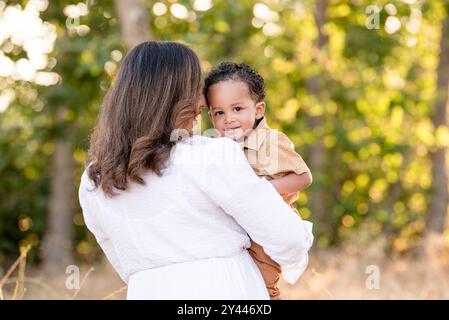 Mother holding son while he is looking over her shoulder Stock Photo