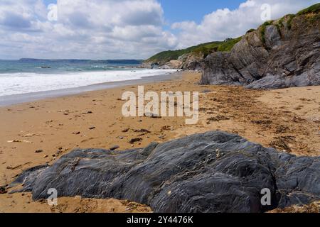 Low tide on a deserted Hemmick beach in Cornwall on a cloudy summer day. Stock Photo