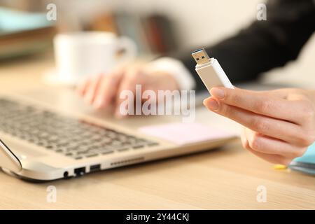 Close up of an executive hand holding usb drive using laptop on a desk at office Stock Photo