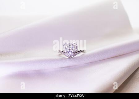 Jewelry silver heart ring with  diamond on a white leather surface Stock Photo