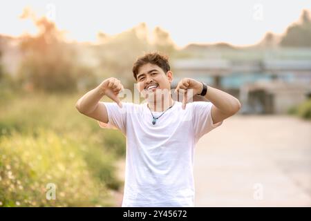 a man standing with a thumbs down. The man acted like someone was underestimating something. set in nature on a sunny afternoon. Stock Photo