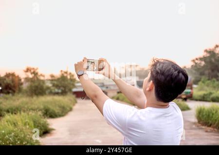 a man who is taking photos of himself and nature in various styles. the man has his back to the camera. set on a sunny afternoon in nature. Stock Photo