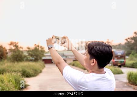 a man who is taking photos of himself and nature in various styles. the man has his back to the camera. set on a sunny afternoon in nature. Stock Photo