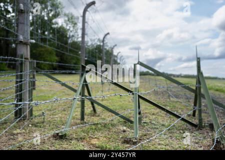 Concentration camp Buchenwald memorial site near Weimar. Focus on the barbed wire in front. Blurred background with watchtower Stock Photo