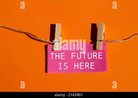 The future is here message written on ripped pink torn paper piece on orange background. Conceptual the future is here symbol. Copy space. Stock Photo