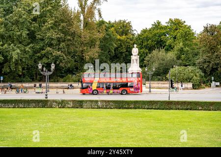 Germany Berlin September 15, 2024. A red double-decker tourist bus rides down the street in the park. The bus is decorated and has drawings on board. Stock Photo