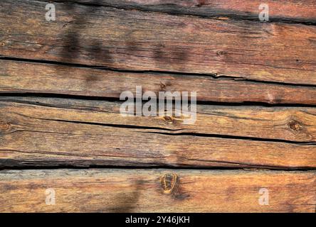 This photo shows a close-up of a weathered wooden surface, with long horizontal wooden planks. The wood exhibits a rich variety of tones from dark bro Stock Photo