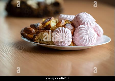 Delicious pastries and pink meringues arranged beautifully on a white plate. Stock Photo