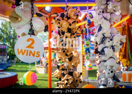 Cute stuffed animal toy prizes hanging on funfair fairground stall. Sign says 2 wins. Stock Photo