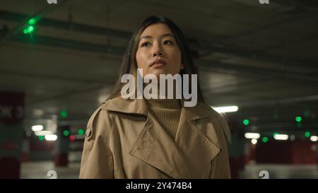 Close up portrait pensive upset serious Asian chinese ethnic woman young girl businesswoman female in dark parking city unhappy customer car owner Stock Photo