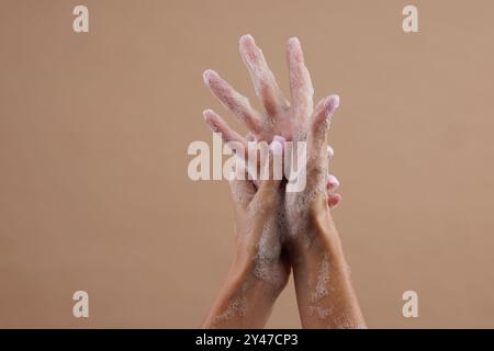 A close-up of two hands lathered with soap, demonstrating hand washing. The hands are positioned in a way that emphasizes the soap bubbles against a n Stock Photo