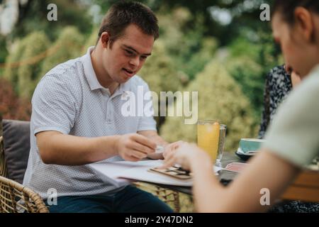 Young man with friends enjoying outdoor cafe visit together Stock Photo