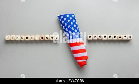 Republicans vs Democrats. Conceptual words written on wooden blocks. American flag and on the sides Republicans and Democrats. Cracked gray background Stock Photo