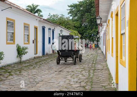 Paraty, Brazil. February 23, 2023. Tourist riding a wagon with horse in the historic district. Stock Photo