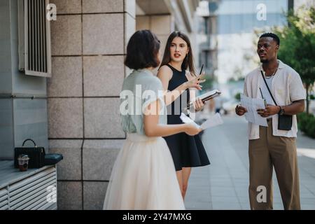 Young professionals discussing project outdoors on city street Stock Photo